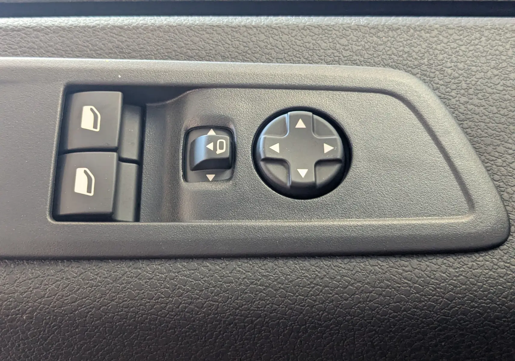 Détail des commandes de réglage des rétroviseurs et vitres sur la porte intérieure noire du Citroën Jumpy Cabine Approfondie gris titane.