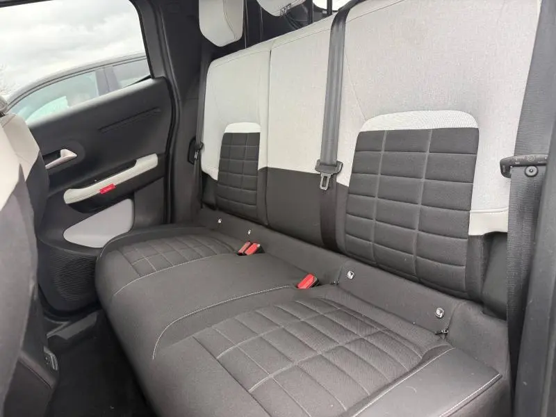 Vue intérieure de la banquette arrière de la Citroën C3 électrique 2025, avec sièges bicolores gris clair et foncé.