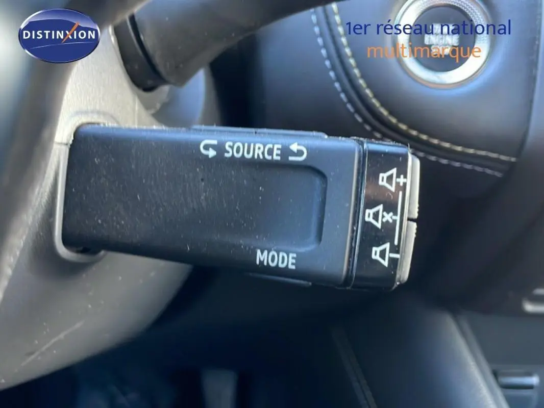 Gros plan sur la commande au volant noir avec boutons source et mode dans l’habitacle d’une Renault Symbioz bleu.