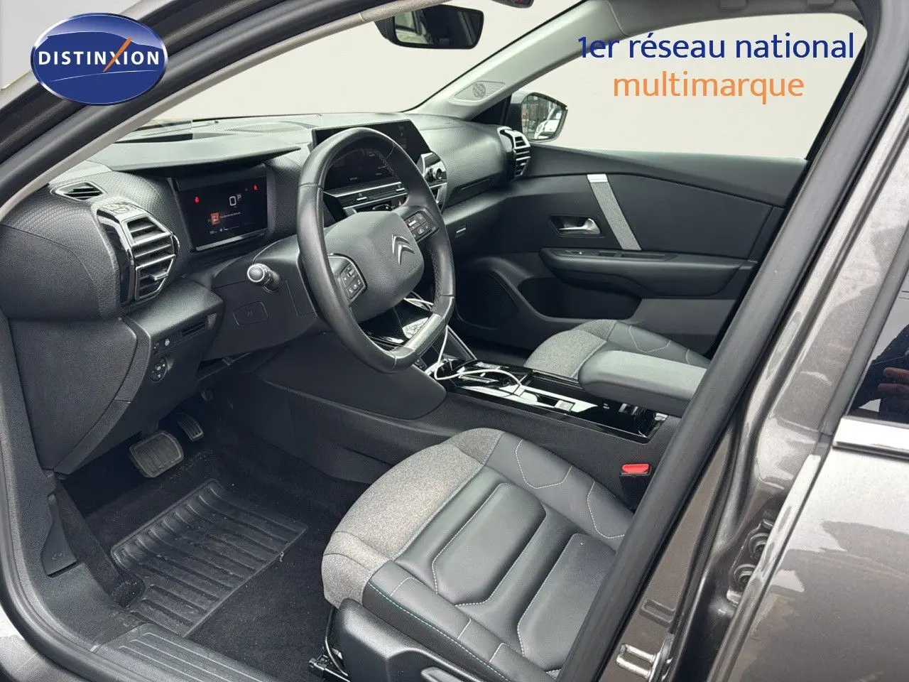 Vue intérieure côté conducteur de la Citroën C4 gris 2021, avec sièges bi-matière cuir et tissu et tableau de bord moderne.