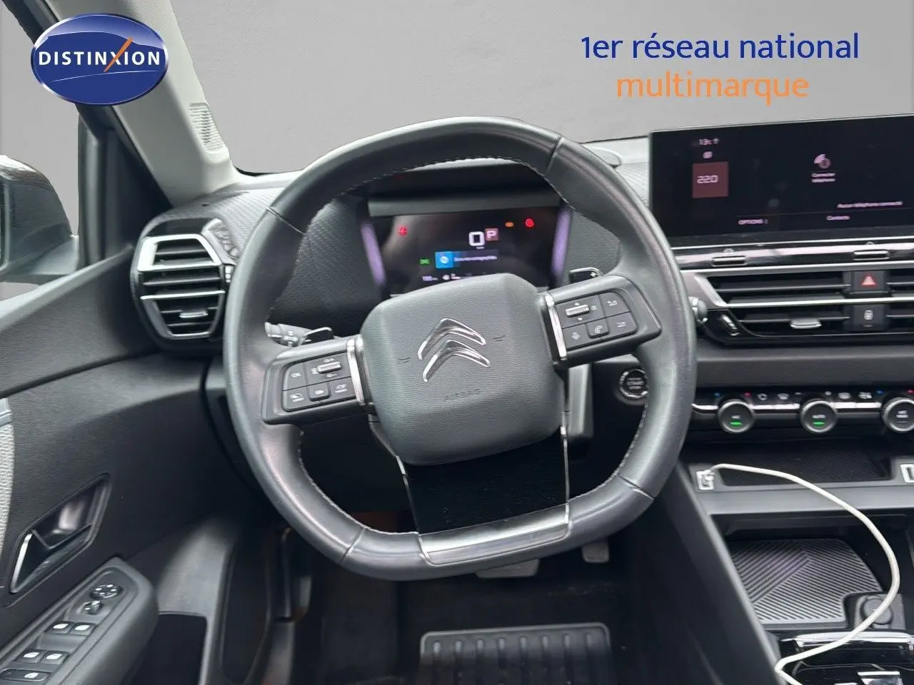 Vue intérieure centrée sur le volant cuir noir et le tableau de bord numérique d'une Citroën C4 gris 2021.