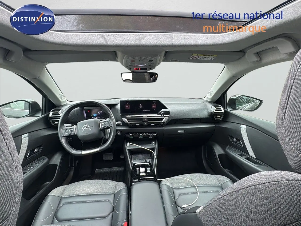 Vue intérieure avant de la Citroën C4 2021, tableau de bord moderne avec écran tactile et sièges gris tissu et cuir.