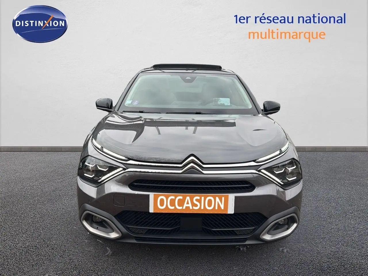 Vue frontale d'une Citroën C4 gris métallisé avec phares LED et calandre distinctive, sur fond neutre.