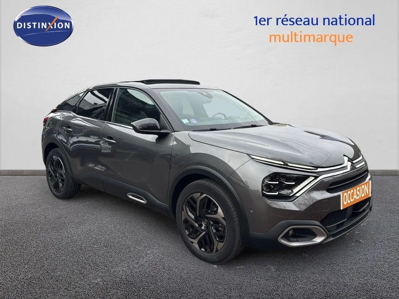 Citroën C4 gris en 3/4 avant droit, avec jantes noires et toit ouvrant panoramique visible.