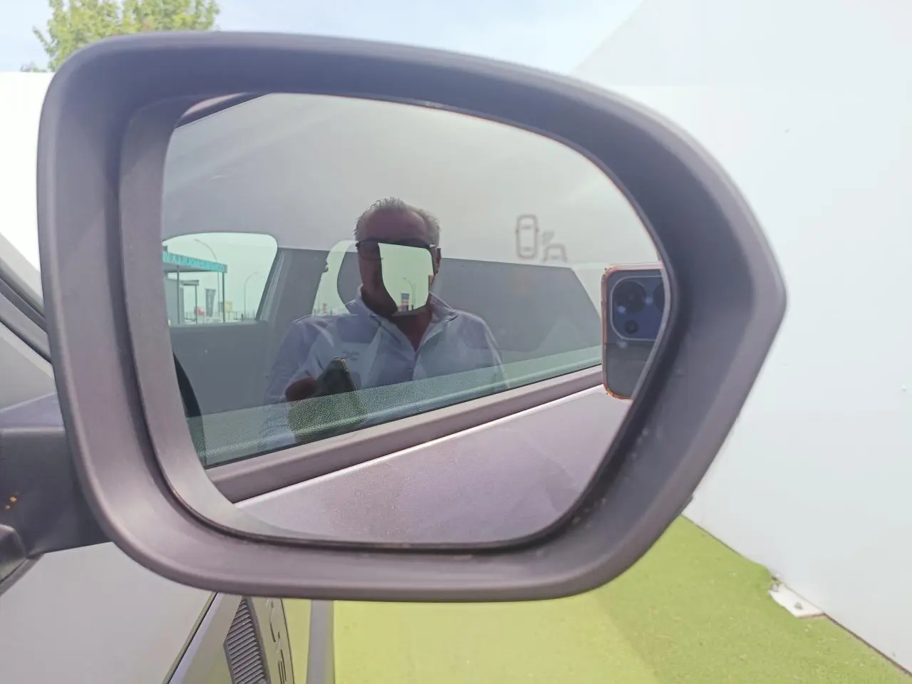 Rétroviseur extérieur côté gauche du Dacia Duster gris schiste métal, avec reflet partiel de l'habitacle et d'une personne.