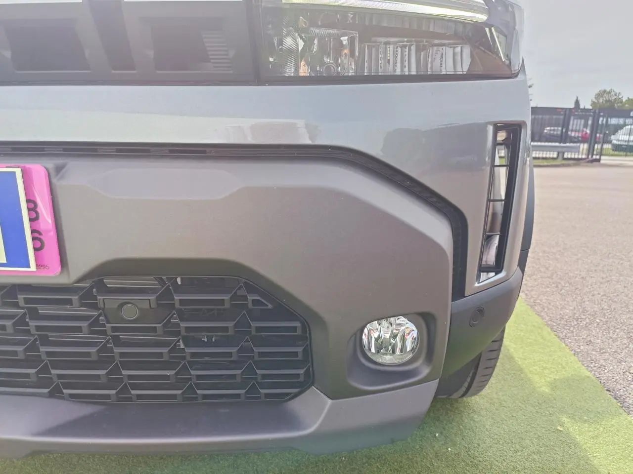 Gros plan sur l’avant droit du Dacia Duster gris schiste, mettant en valeur la calandre et le projecteur antibrouillard.