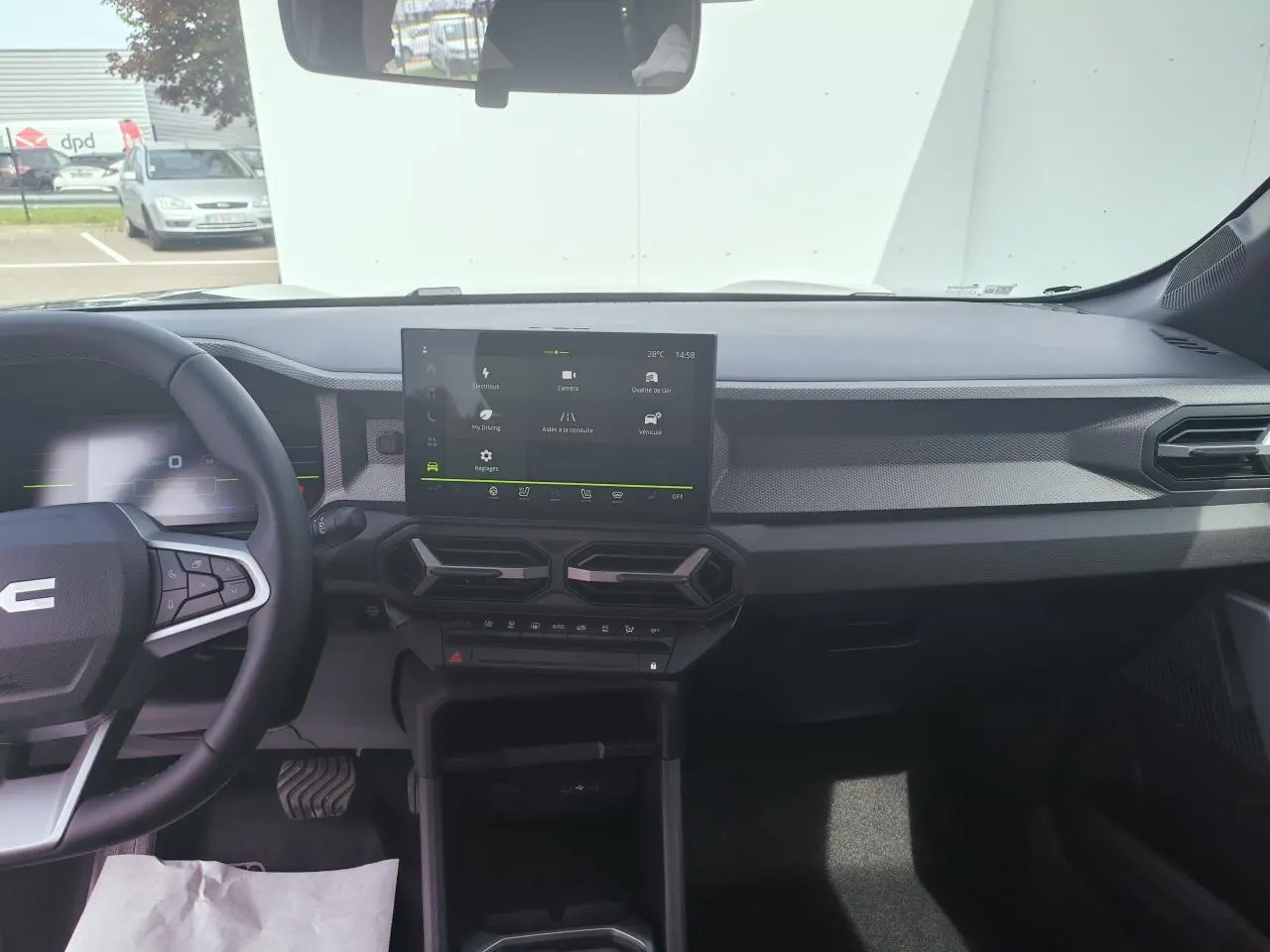 Vue intérieure avant du tableau de bord du Dacia Duster III gris schiste, avec écran tactile central et volant multifonction.