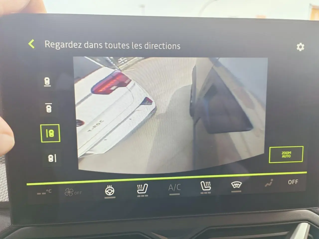 Écran tactile intérieur montrant la caméra multivues du Dacia Duster III gris schiste, vue latérale et arrière du véhicule.