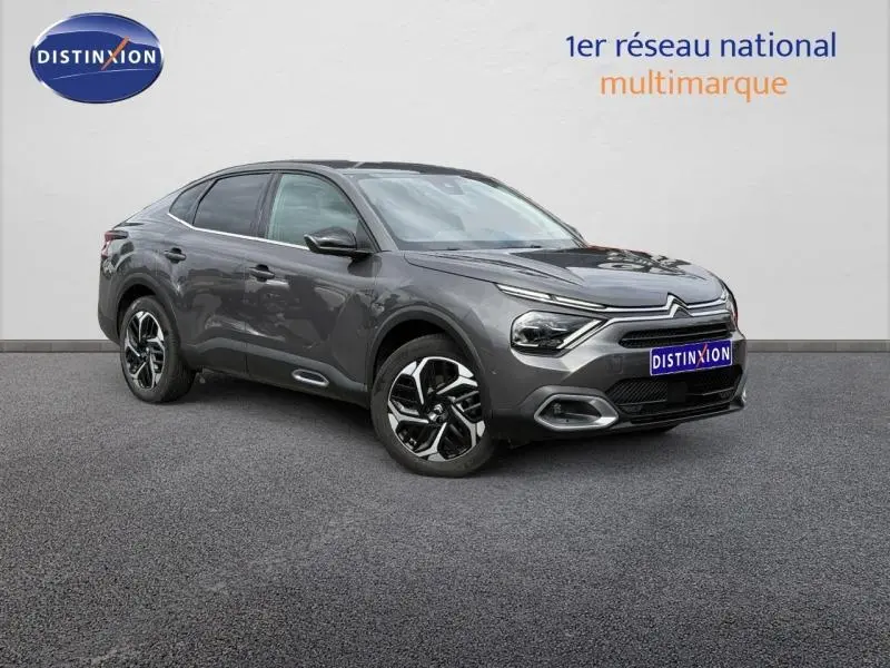 Citroën C4 X gris Platinium en 3/4 avant droit, avec signature lumineuse distinctive et jantes bicolores.