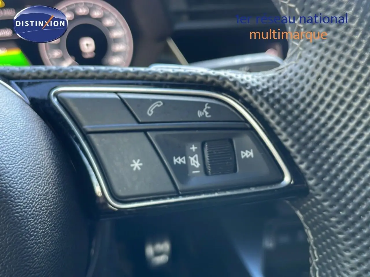 Gros plan sur les commandes multifonctions côté gauche du volant d’un Audi A3 Sportback blanc Ibis 2025.