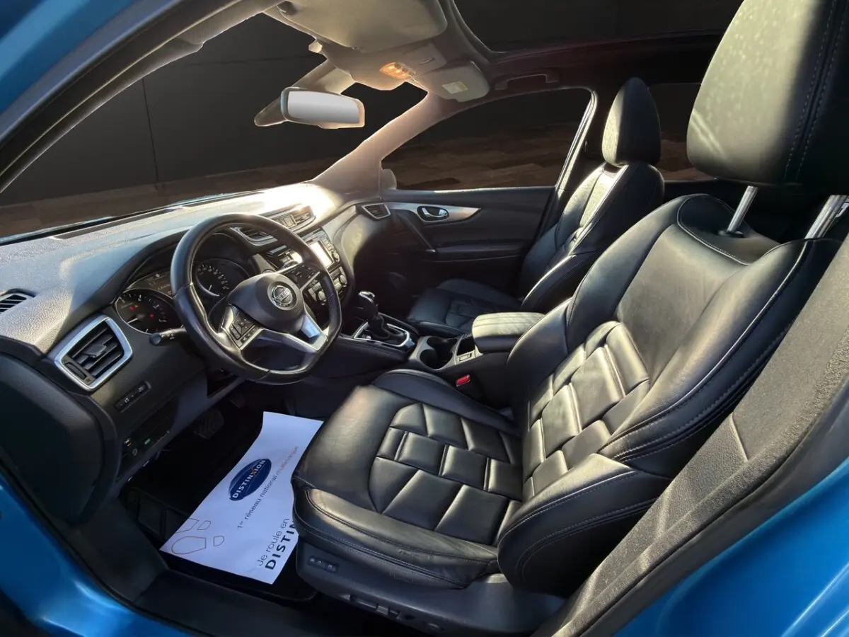Vue intérieure côté conducteur du Nissan Qashqai bleu 2018, sièges cuir noirs et tableau de bord moderne.