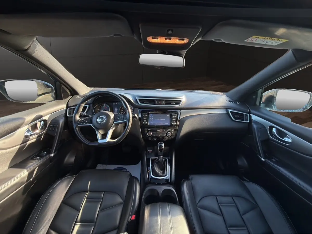 Vue intérieure avant du Nissan Qashqai Tekna+ 2018, montrant le tableau de bord noir et le volant cuir multifonctions.