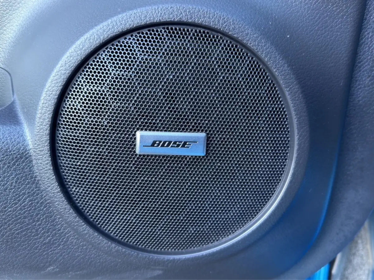 Gros plan sur le haut-parleur Bose intégré dans la porte intérieure d’un Nissan Qashqai bleu 2018.