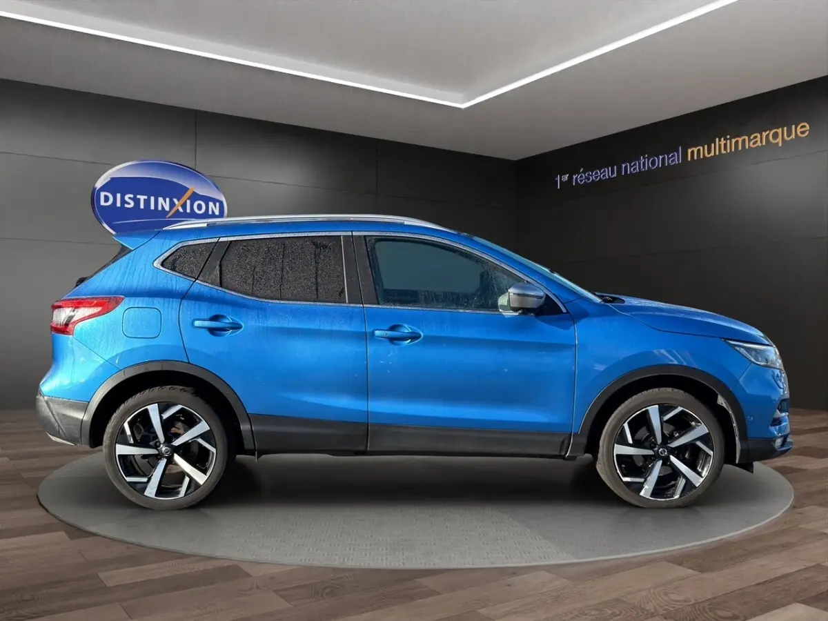 Vue latérale droite d'un Nissan Qashqai bleu 2018 avec jantes alliage et vitres teintées en showroom.