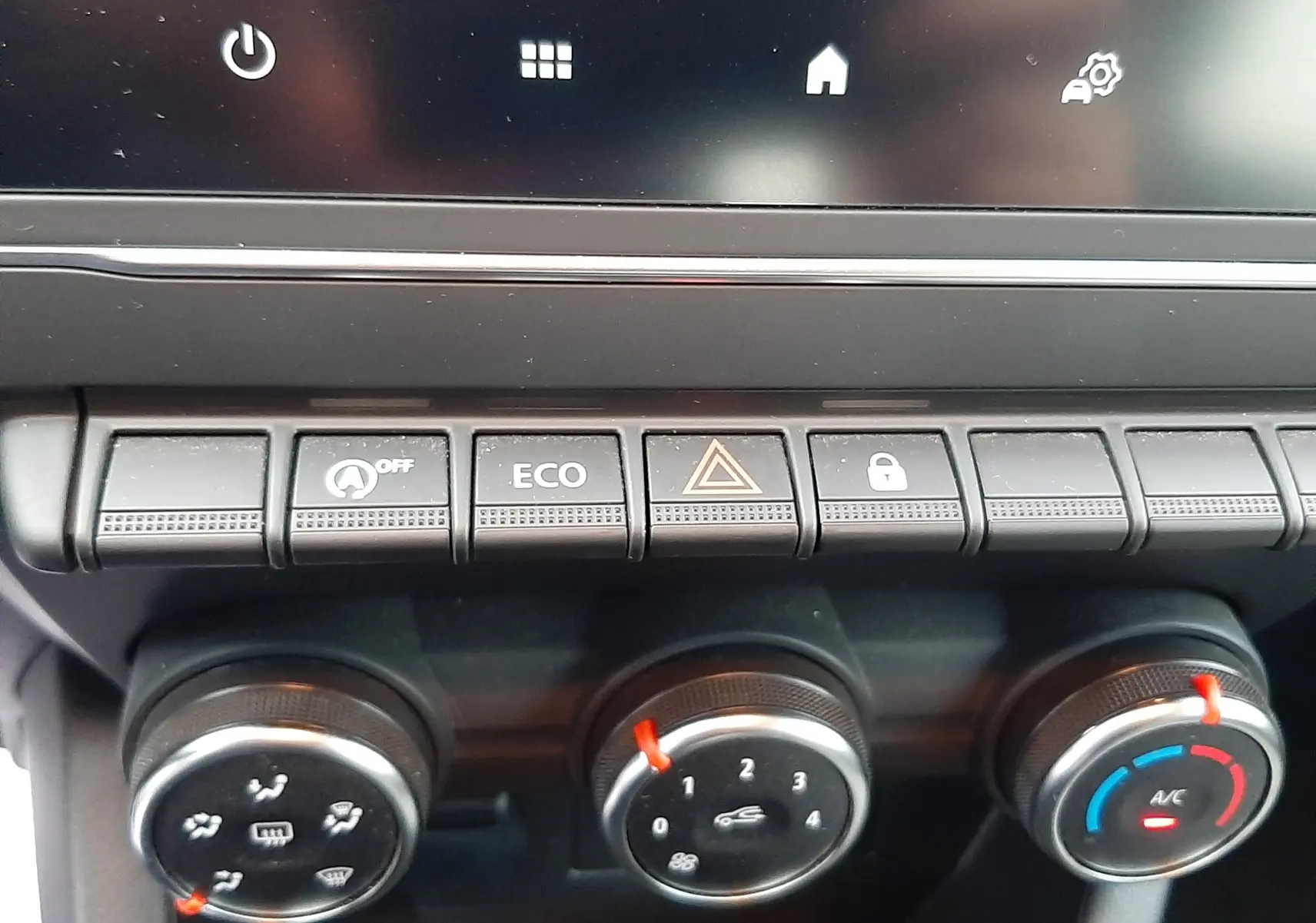 Gros plan sur les commandes de climatisation et boutons de fonction du tableau de bord d'une Renault Clio V gris schiste.