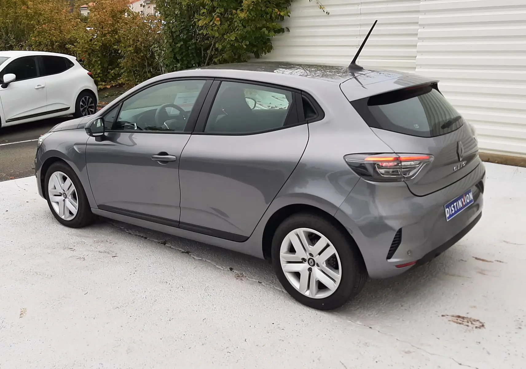 Renault Clio V TCE 90ch Evolution gris schiste vue 3/4 arrière côté gauche sur fond extérieur urbain.