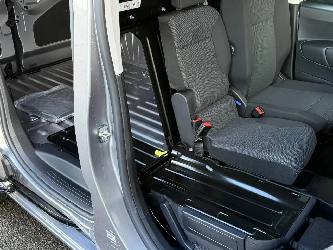 Vue intérieure côté droit du Citroën Berlingo gris Artense, montrant la banquette passager rabattue et l'espace de chargement.