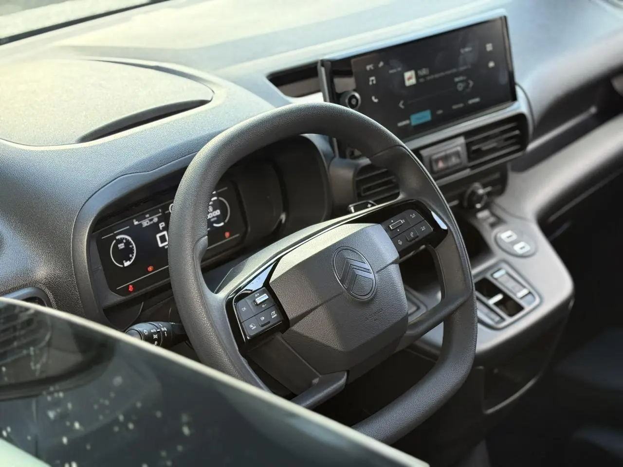 Vue rapprochée du volant multifonctions et tableau de bord numérique du Citroën Berlingo gris Artense 2025.