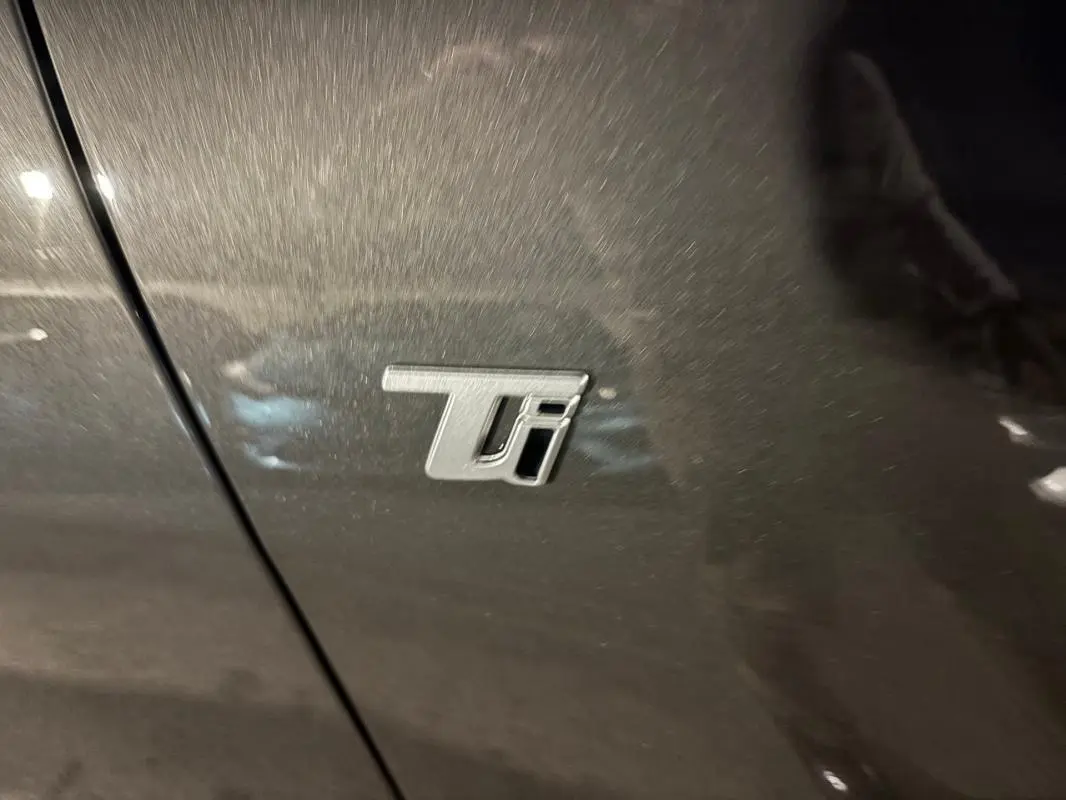 Gros plan sur l'emblème Ti sur la porte gris métallisé de l'Alfa Romeo Tonale 2023 hybride rechargeable.