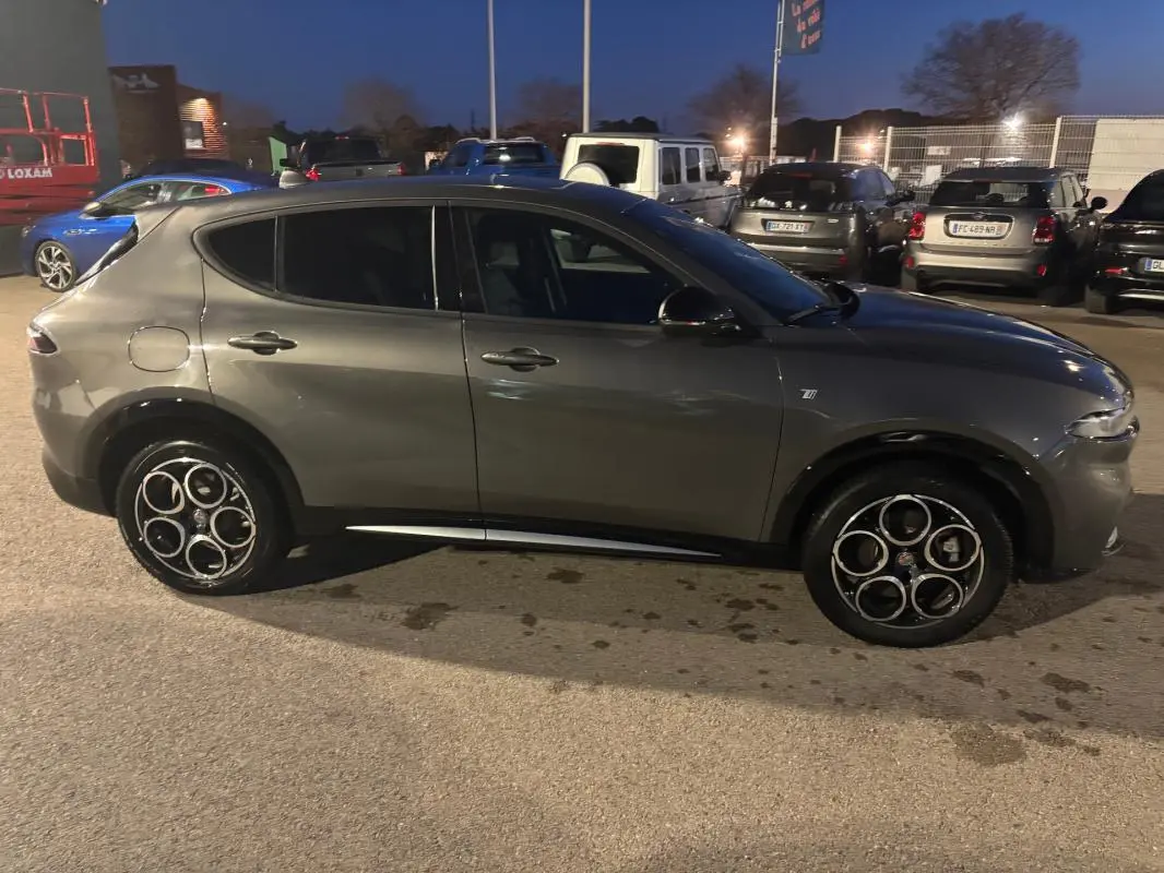Vue de profil côté gauche d'une Alfa Romeo Tonale gris métallisé 2023 avec jantes alliage distinctives en cercle.
