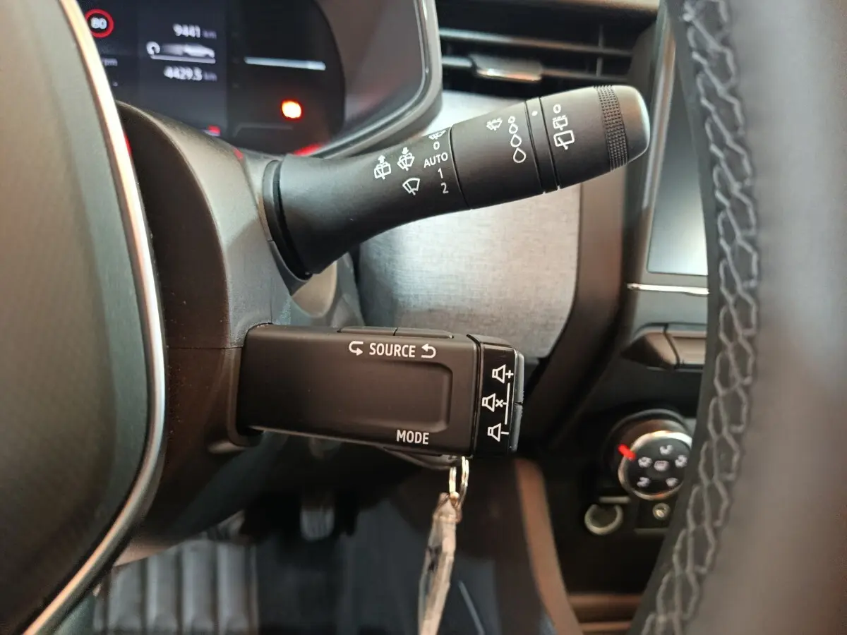 Gros plan sur les commandes au volant d’une Renault Clio noire 2025, avec affichage multifonctions et volant cuir.