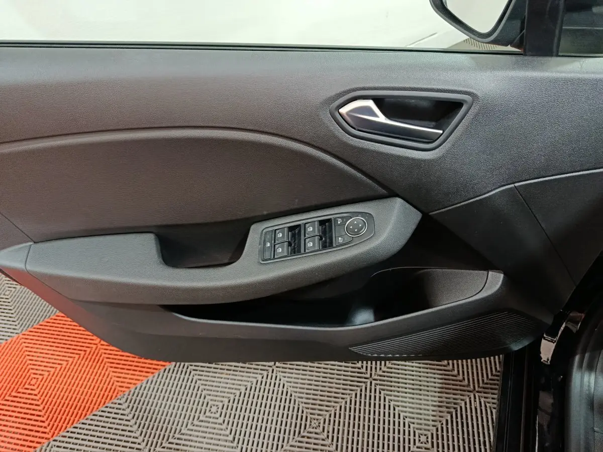 Vue rapprochée de la porte avant gauche noire de la Renault Clio 2025, avec commandes électriques des vitres et rétroviseurs.