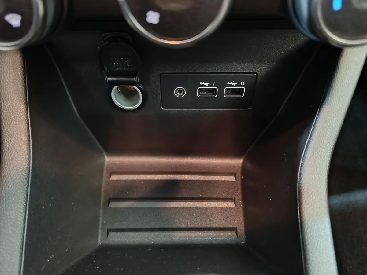 Gros plan sur la console centrale de la Renault Clio noire 2025, montrant prises USB et prise 12V.