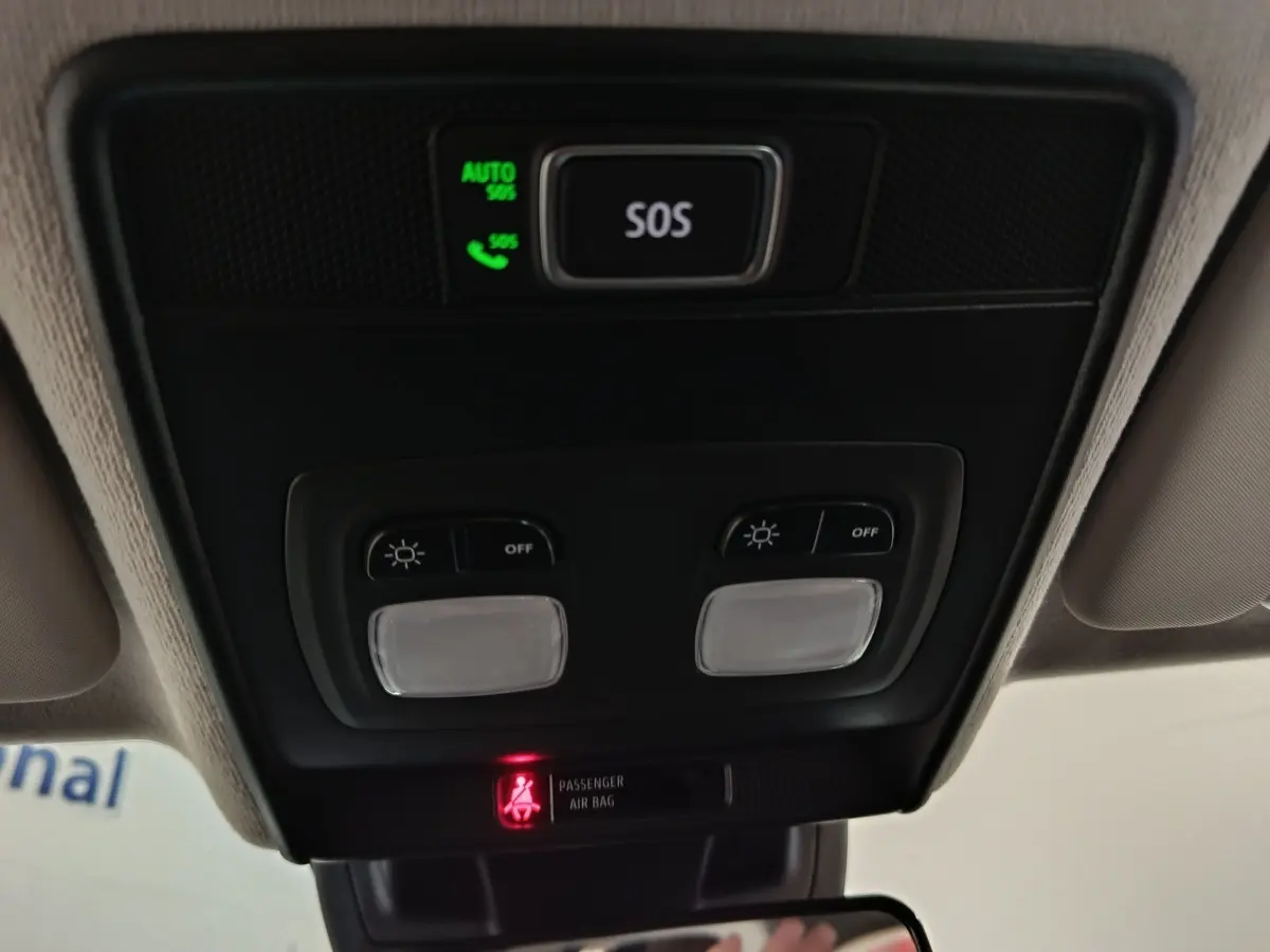 Vue intérieure en gros plan du plafonnier avec boutons d’éclairage et alerte airbag passager de la Renault Clio noire.