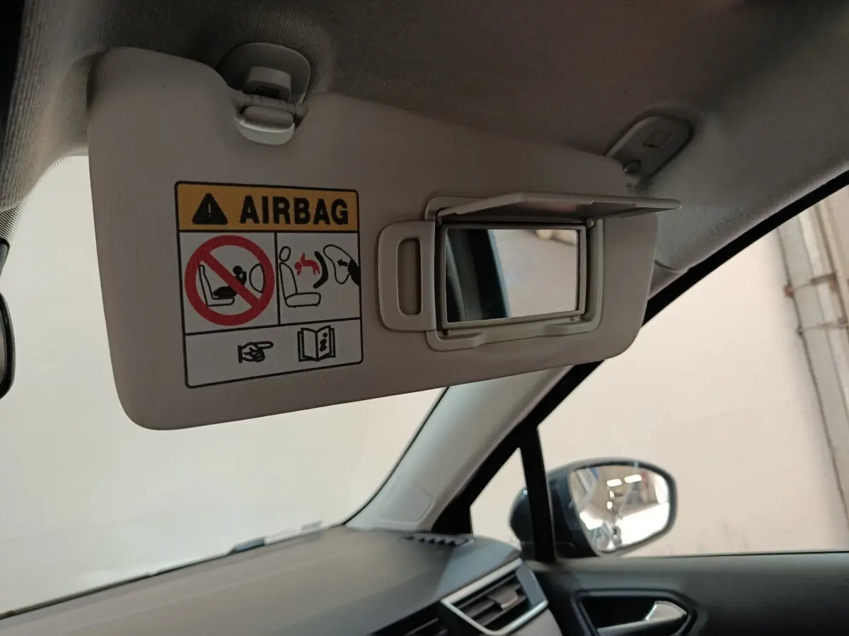 Détail intérieur montrant le pare-soleil côté conducteur avec miroir et avertissement airbag dans une Renault Clio noire.