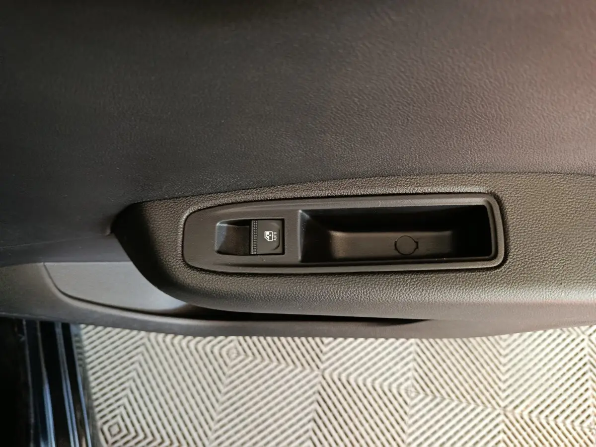 Gros plan sur la commande de lève-vitre côté conducteur de la Renault Clio noire Evolution Blue dCi 100 -25, intérieur.