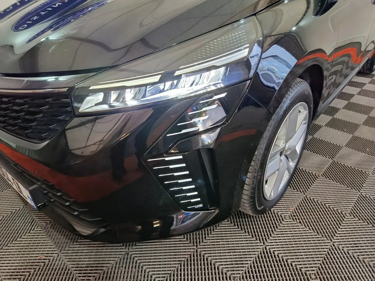 Gros plan sur l'avant droit de la Renault Clio noire 2025, mettant en valeur ses phares LED et la calandre moderne.