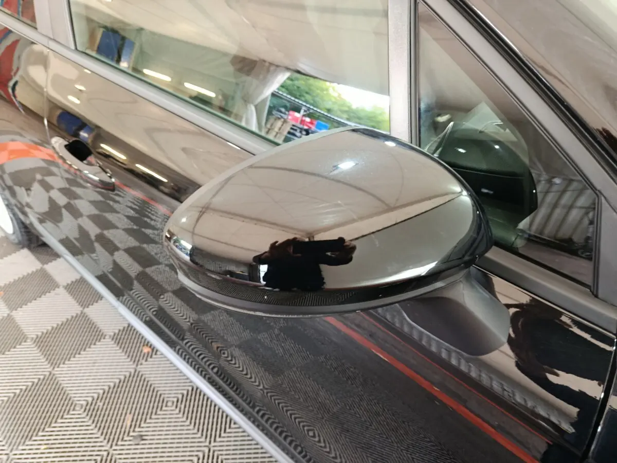 Rétroviseur côté conducteur noir brillant de la Renault Clio Evolution Blue dCi 100, vue rapprochée sur la portière avant.