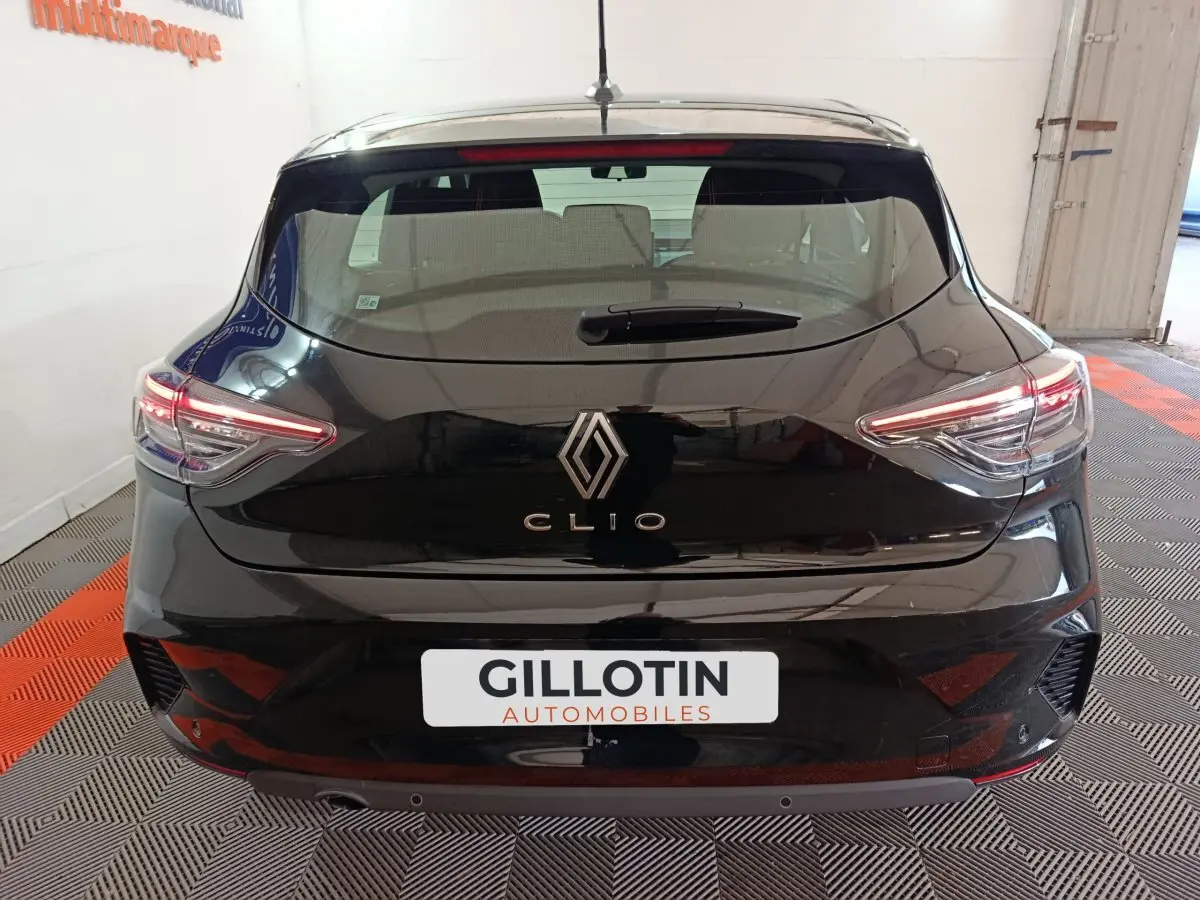 Vue arrière d'une Renault Clio noire 2025 avec feux LED allumés dans un garage intérieur.