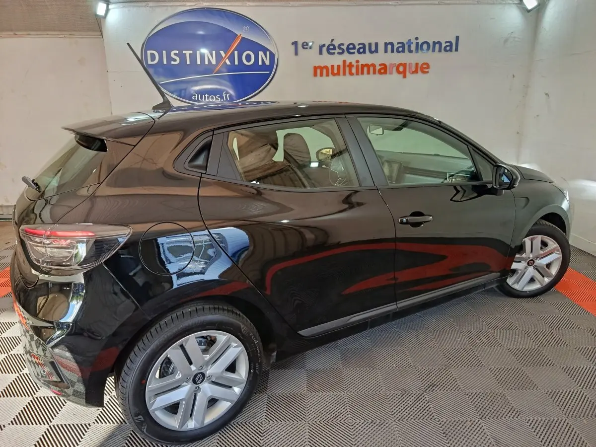 Vue côté droit arrière d'une Renault Clio noire 2025 Evolution Blue dCi 100 dans un showroom avec éclairage intérieur.