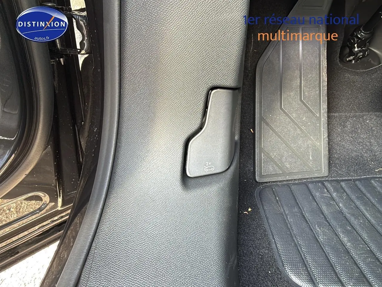 Détail intérieur côté gauche au niveau du plancher avec commande d'ouverture du coffre sur Peugeot 3008 gris titane 2024.