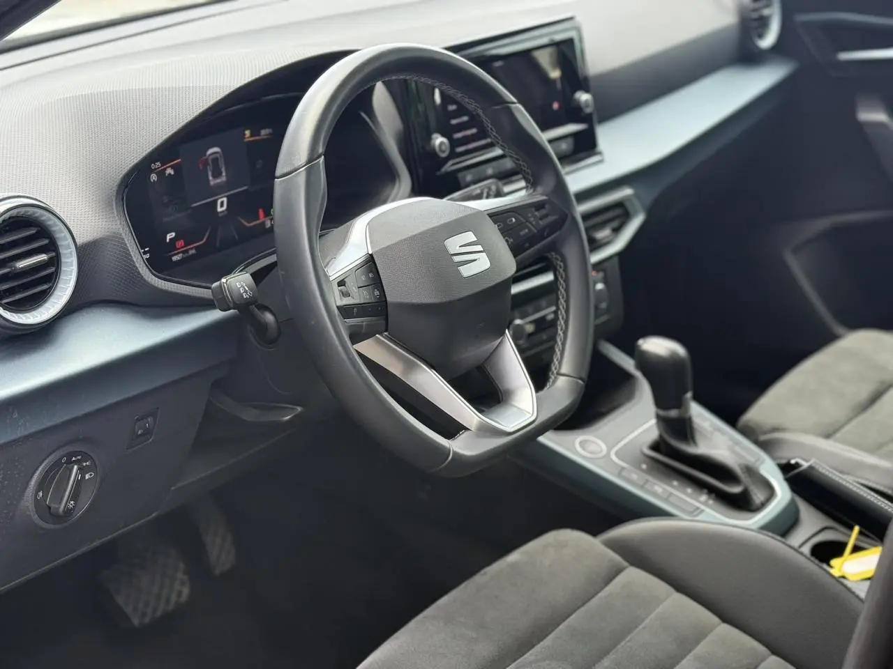 Vue intérieure côté conducteur du tableau de bord et volant noir du SEAT Arona 2025 avec sellerie suédine.