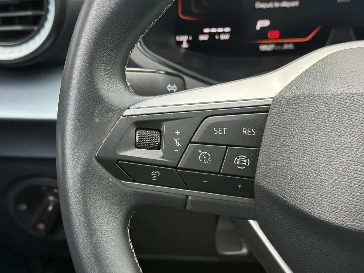 Gros plan sur les commandes du régulateur de vitesse au volant d’un SEAT Arona 2025, intérieur noir.
