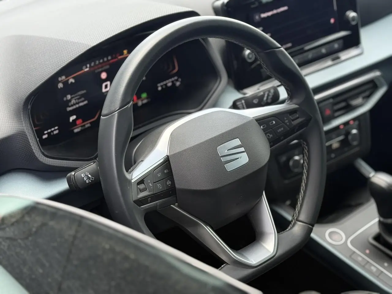 Vue rapprochée du volant noir et du tableau de bord digital du SEAT Arona 2025, avec console centrale visible.