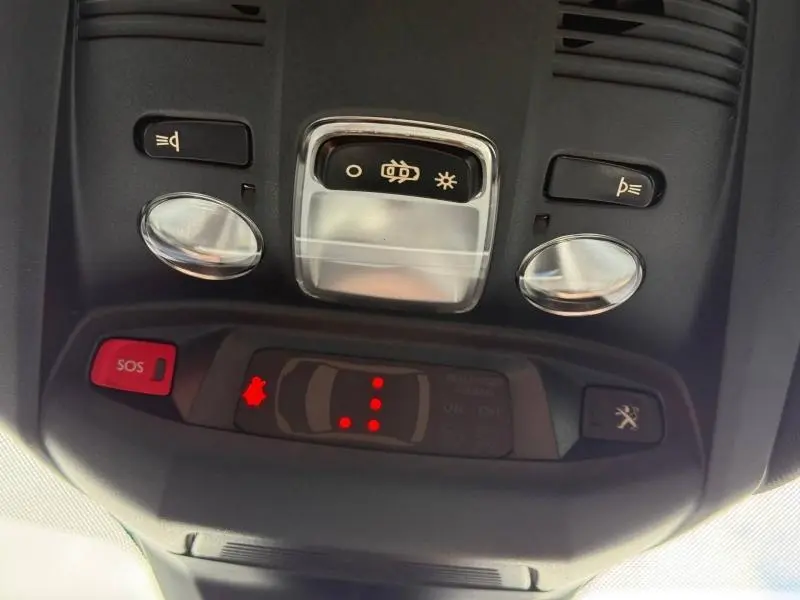 Vue en gros plan du panneau de commandes intérieures au plafond du Peugeot 3008 Gris Platinium, avec bouton SOS rouge et éclairage.