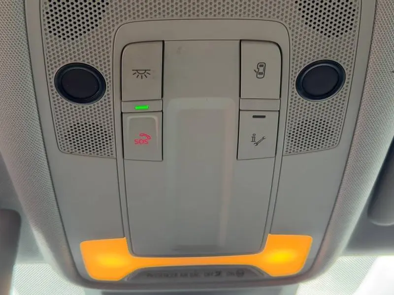 Vue en gros plan du panneau de commande de toit intérieur avec éclairage orange, boutons SOS et commandes de lumière dans un Audi A1 Sportback noir Mythic métallisé.