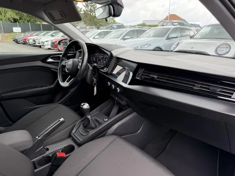 Vue intérieure côté conducteur de l'Audi A1 Sportback 25 TFSI 95ch Advanced 2023 avec tableau de bord numérique et boîte manuelle.