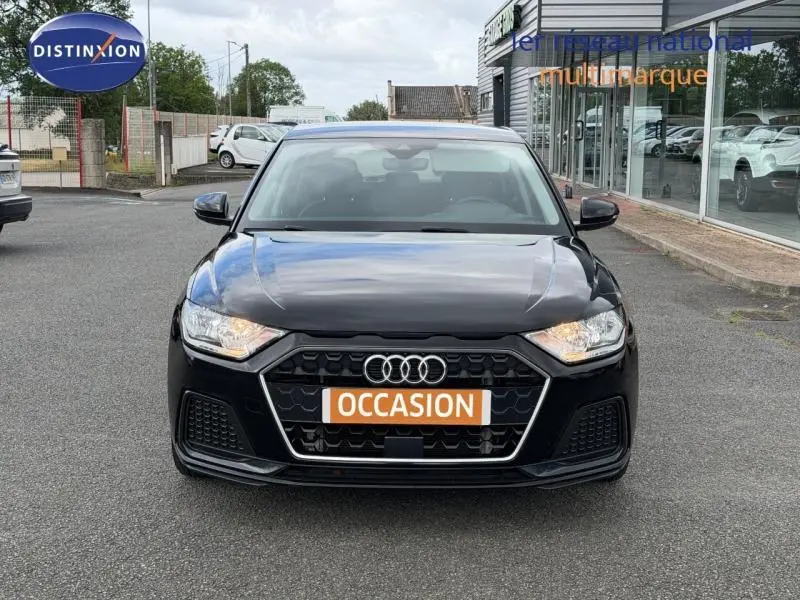 Audi A1 Sportback 25 TFSI noir Mythic métallisé vue de face avec calandre hexagonale et phares allumés.