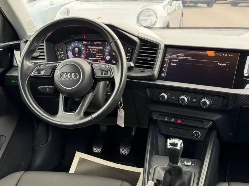 Intérieur Audi A1 Sportback 25 TFSI 95ch 2023, vue du poste de conduite avec volant multifonction et écran tactile central.