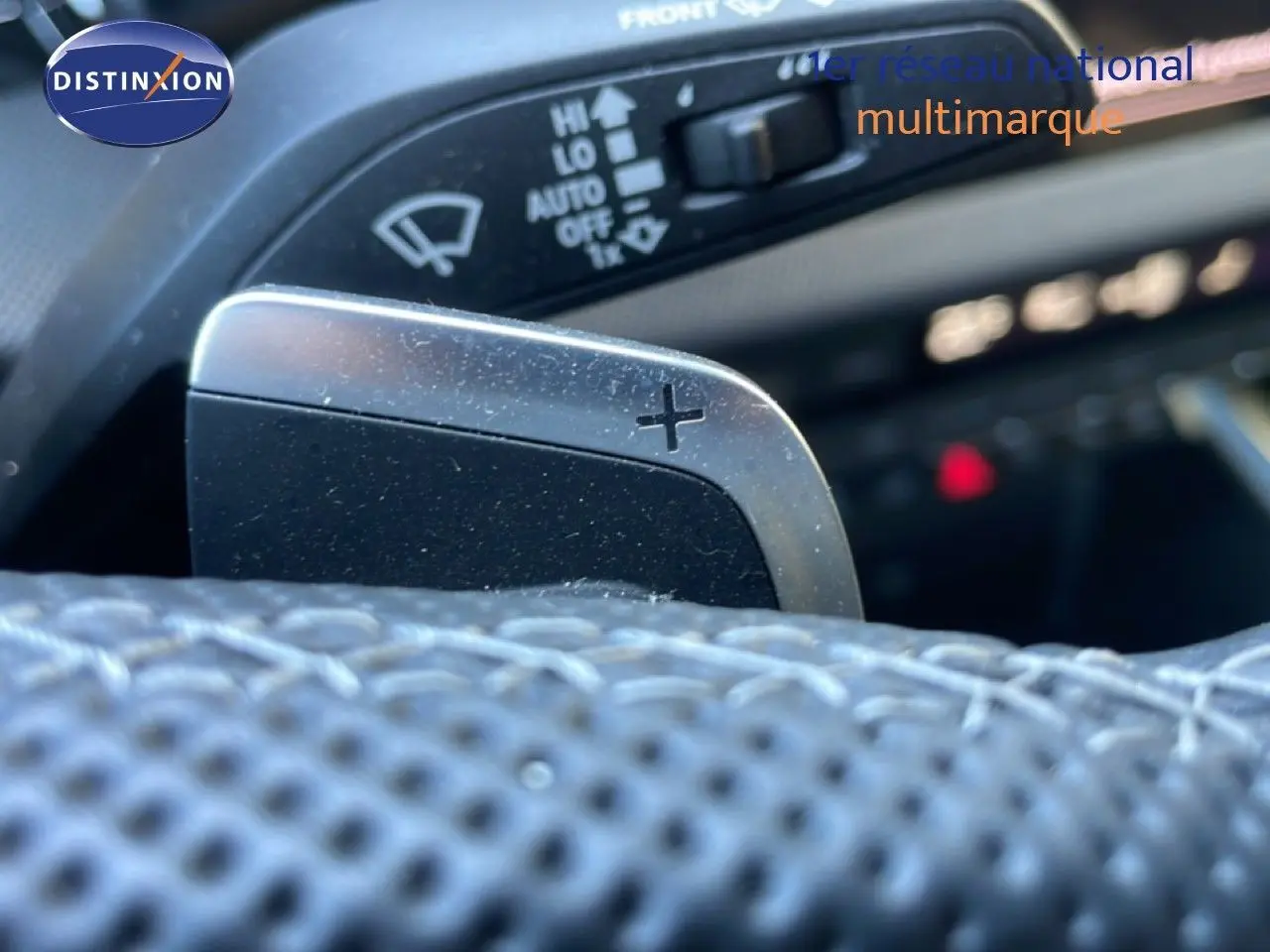 Gros plan sur la palette de changement de vitesse "+" en aluminium brossé dans l'habitacle d'une Audi A3 Sportback noire.