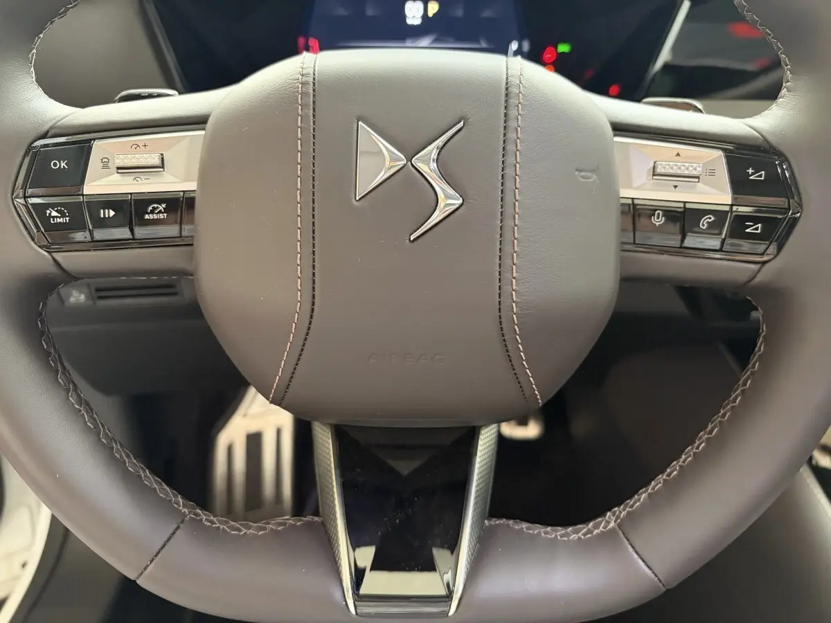 Gros plan sur le volant cuir marron du DS4 2024 avec commandes multifonctions et logo DS central.