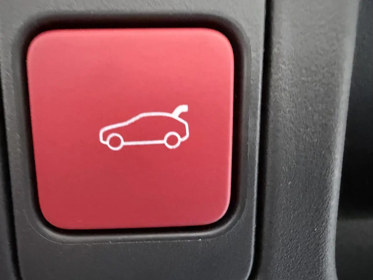 Bouton rouge intérieur du DS4 2024 avec pictogramme de coffre ouvert, vue en gros plan.