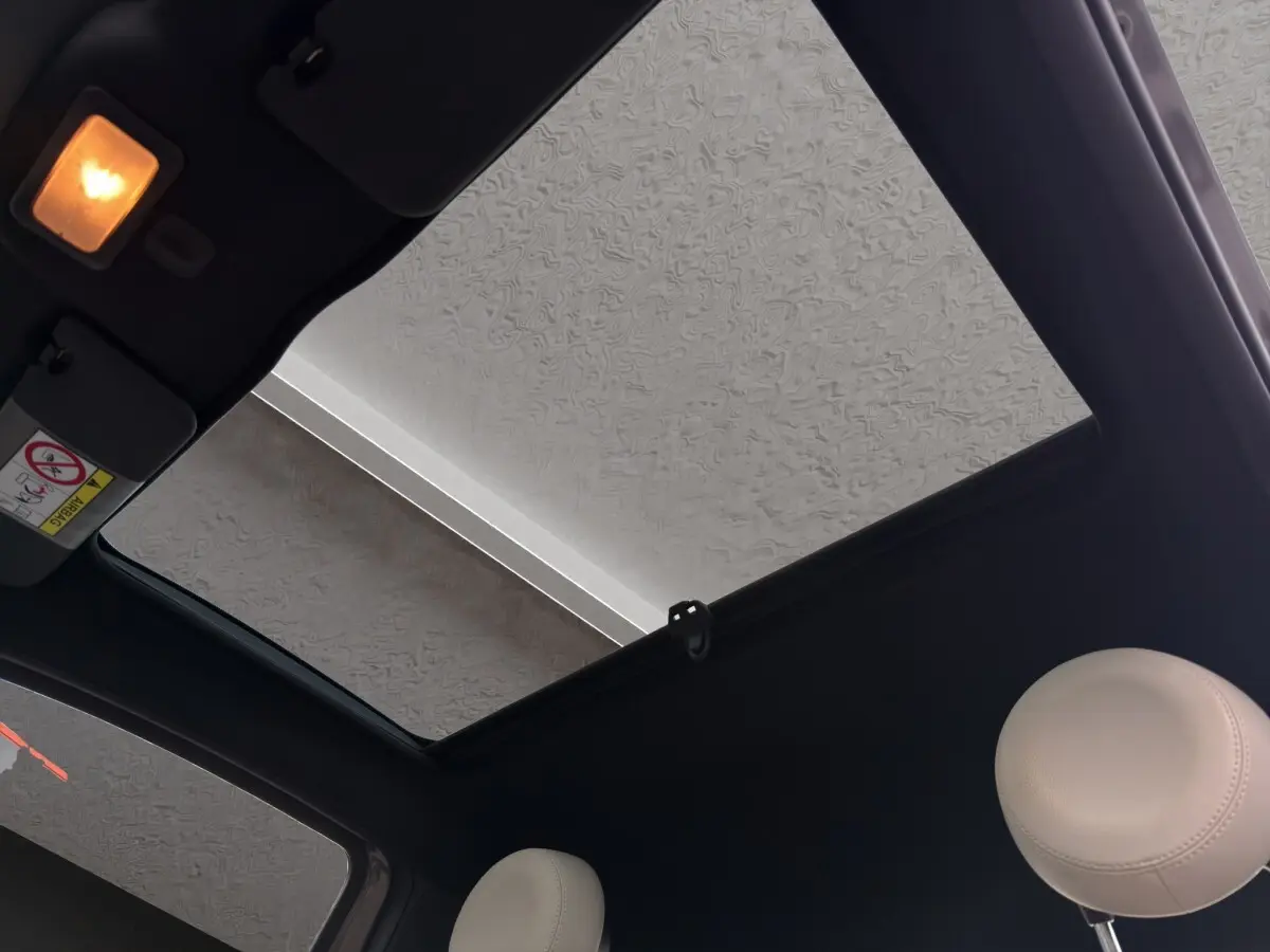 Vue intérieure du toit ouvrant panoramique et des appuie-têtes beige du Fiat 500 gris foncé 2020.