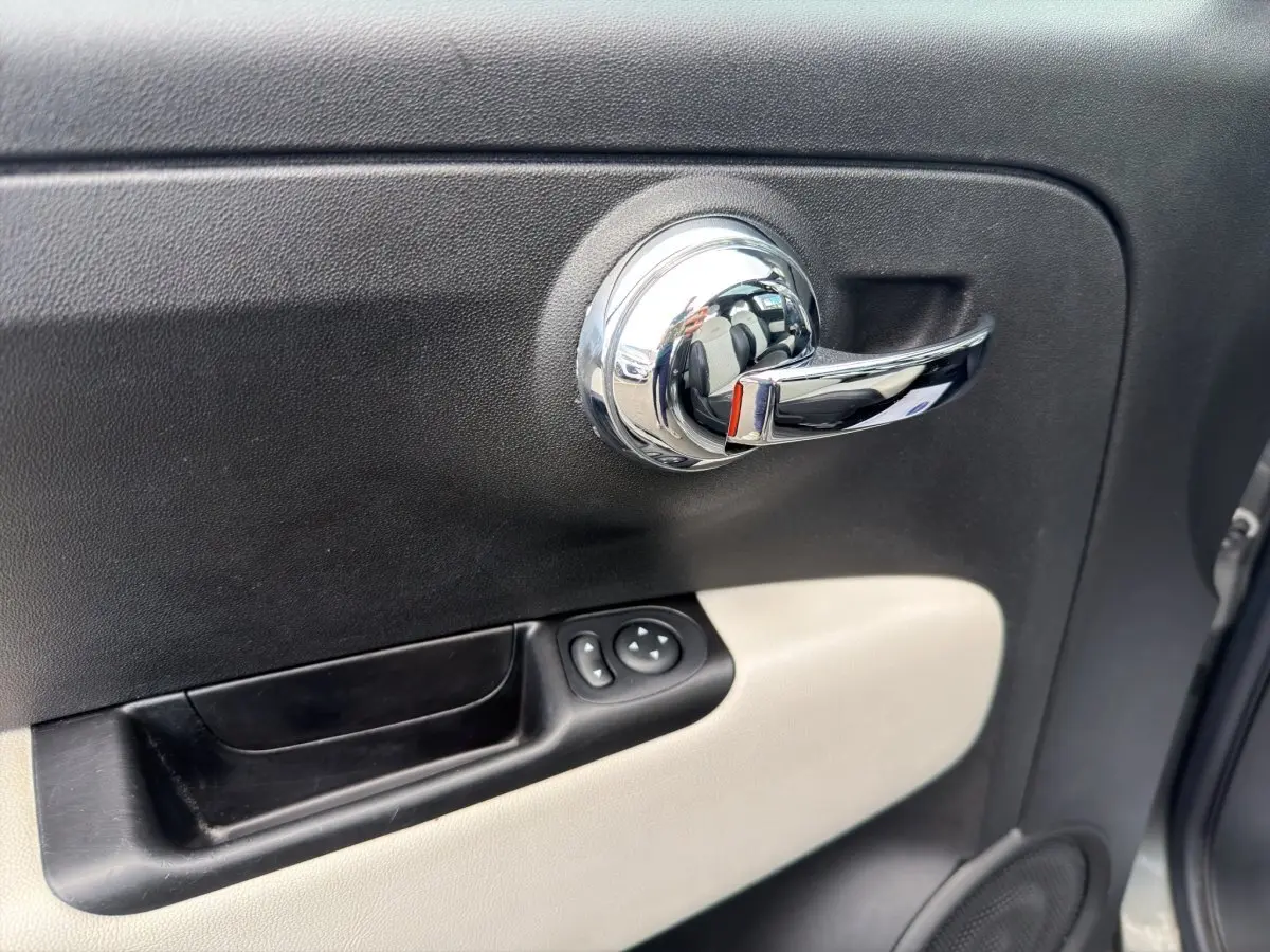 Poignée de porte intérieure chromée côté conducteur avec panneau noir et beige sur Fiat 500 gris foncé 2020.