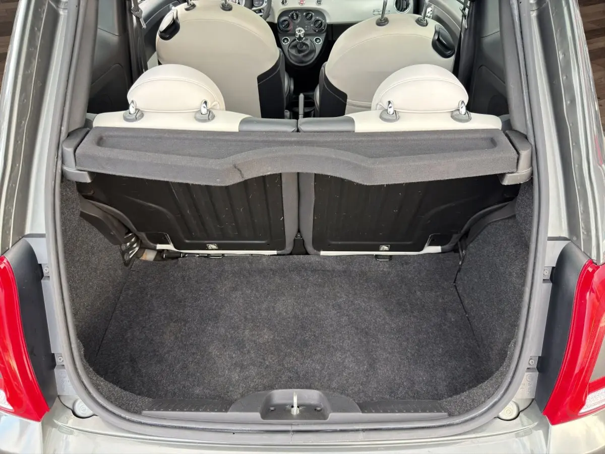 Coffre ouvert vu de l'arrière d'une FIAT 500 gris foncé avec banquette arrière beige et tablette de coffre.