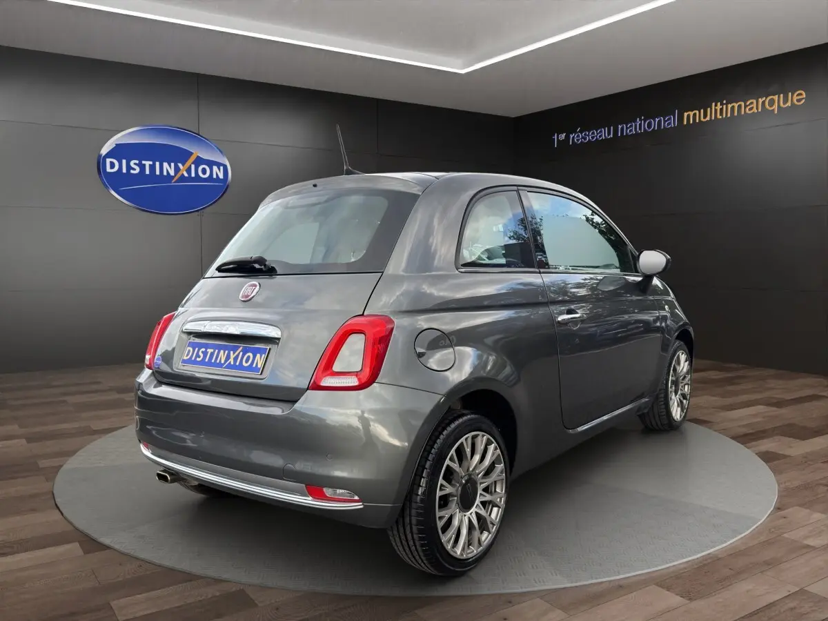 Vue 3/4 arrière droite d'une Fiat 500 gris foncé avec jantes alliage et feux arrière LED, en showroom.